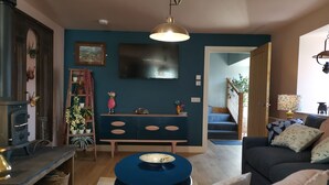 A cozy living room with a fireplace, a blue sofa, a coffee table, and a staircase leading to another level.