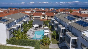 A residential area with modern buildings, a swimming pool, and solar panels. - Adonis Luxury Village (Kassandra)