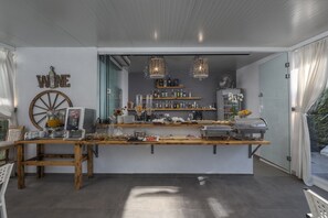 A bar area with a wooden counter, shelves with bottles, a fan, and a sign that says "WINE".
