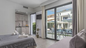 A modern hotel room with two beds, a kitchenette, and a balcony with outdoor seating. - Adonis Luxury Village (Kassandra)