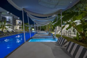 A pool area with lounge chairs and a canopy structure.