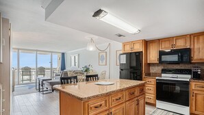 Eine Küche mit Holzausstattung, einer Arbeitsplatte aus Granit, einem schwarzen Kühlschrank, einer Mikrowelle und einem Backofen.