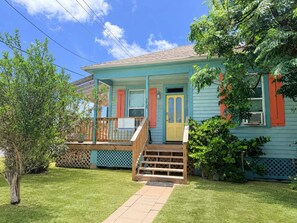 A two-story house with a porch, a front door, and a staircase leading to the second floor. - Casa Azul - 2 Blocks to Beach, Near Historic Strand, Private Yard! (Galveston)