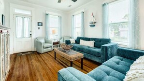 Un salon spacieux avec un canapé bleu, un fauteuil blanc et une table basse.