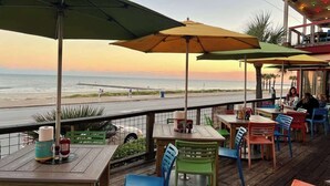 Un restaurant en bord de mer avec une terrasse, des tables et des parasols.