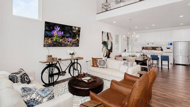 Ein modernes Wohnzimmer mit einer Couch, einem Couchtisch und einem Essbereich mit Stühlen. In der Ecke ist ein Fahrrad zu sehen.