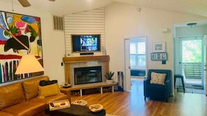 A living room with a fireplace, a television, a sofa, and a coffee table. - CB House (Bike Trail, Brewery, Boardwalk, Park) (Carolina Beach)