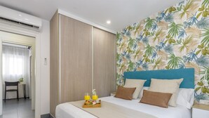 Habitación de hotel con cama, bandeja de desayuno y papel tapiz tropical.