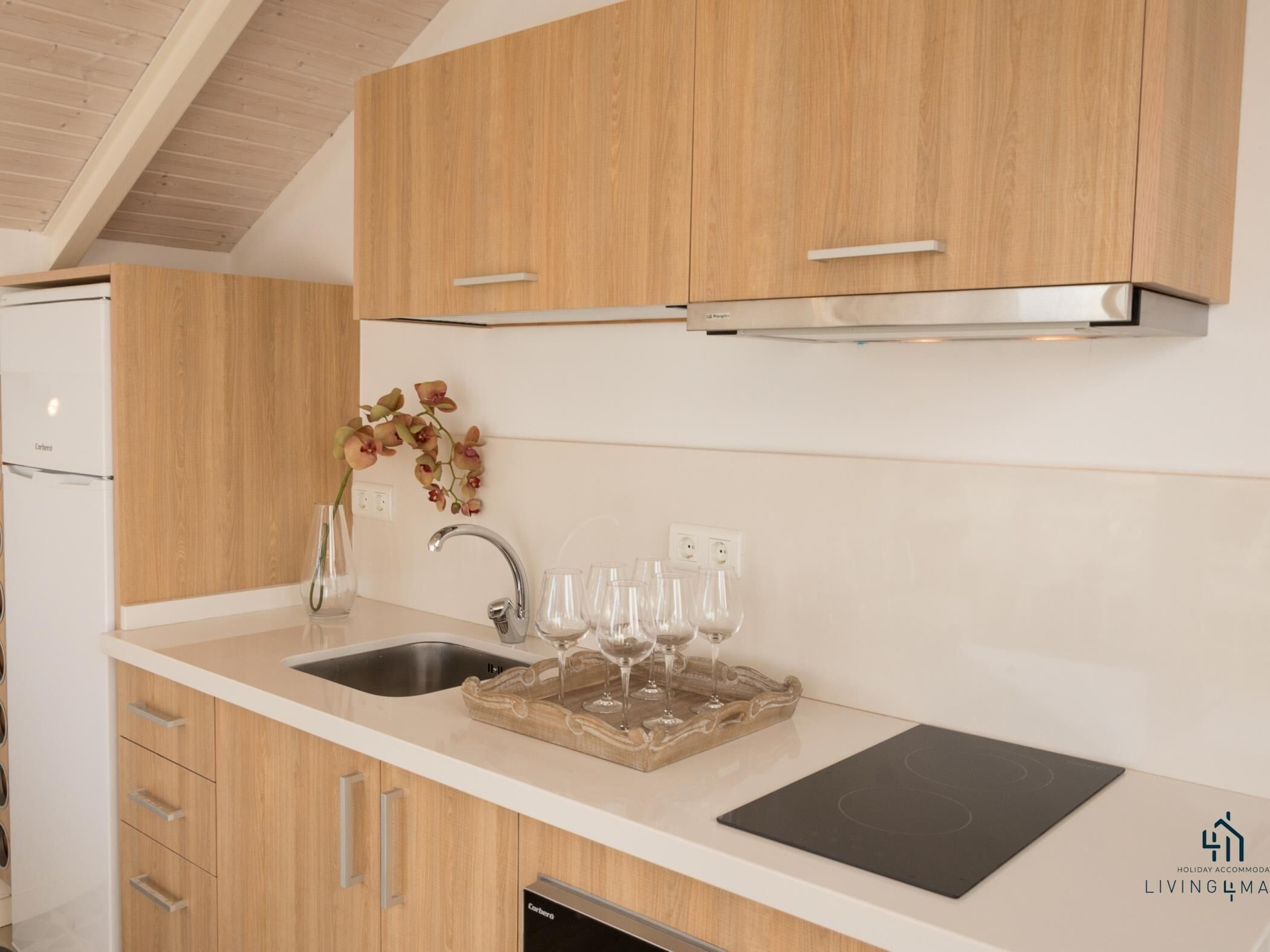 A modern kitchen with wooden cabinets, a stainless steel sink, and a built-in oven.