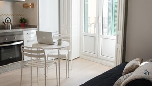 Una cocina moderna con armarios blancos, una campana extractora de acero inoxidable y un ordenador portátil sobre una mesa blanca.