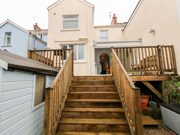 A wooden staircase leading to a balcony with a view of a neighboring building.