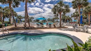 A pool area with lounge chairs, palm trees, and a clear blue sky. - 237 Shorewood Villas - Ocean Views - Exceptional Update - Discounted Rates! (Hilton Head Island)