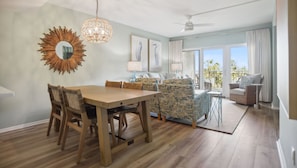 A spacious living area with a wooden dining table, patterned sofas, and a balcony with a view.