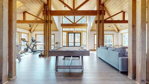 Ein geräumiges Zimmer mit Poolbillard, einer Couch und Fitnessgeräten.