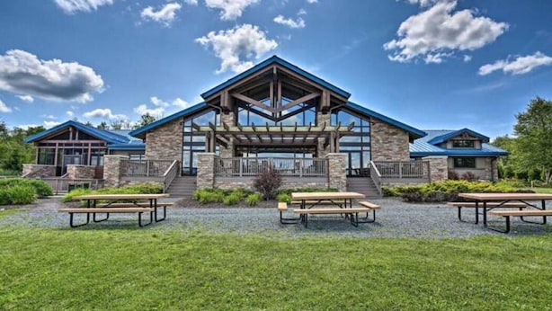 Een lodge met een stenen gevel, een overdekt terras en picknicktafels op de voorgrond.