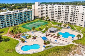 A hotel with multiple swimming pools, a tennis court, and a large building with balconies. - Gulf View Getaway | Beach + Heated Pool | Sleeps 6 (Gulf Shores)