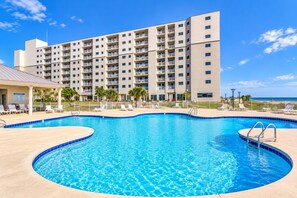 A hotel with a swimming pool, multiple balconies, and a view of the ocean.