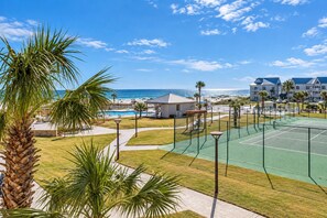 Un resort con cancha de tenis, piscina y vista al océano.