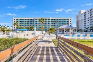 A hotel with a pool area, a wooden boardwalk, and a large building with multiple balconies.