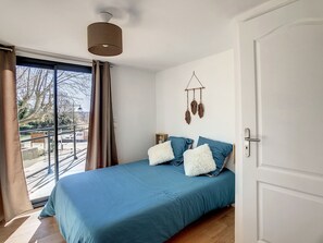 A bedroom with a large bed, a view of the outdoors, and a hanging decoration. - View of the Canal du Midi - Comfortable apartment for 6 people (La Redorte)