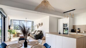 Una cocina moderna con armarios blancos, encimera de madera y una lámpara colgante.