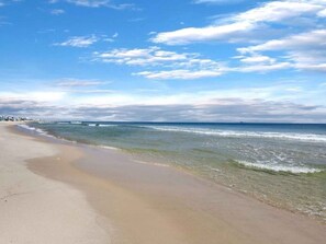 A beach with clear skies and gentle waves. - Brighton by the Sea | Dog Friendly Vacation Home w/ Pool | Steps to the Sand (Gulf Shores)