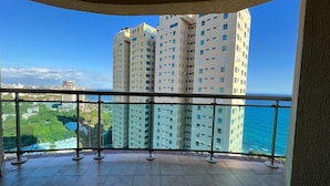 A balcony with a view of tall buildings and a body of water. - Exclusive 3 BDR, Gym & Pool, Sea view Condo (Santo Domingo)