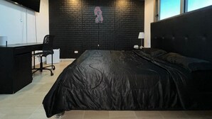 A bedroom with a black headboard, a bed with a black cover, a desk with a chair, and a neon sign on the wall. - Exclusive 3 BDR, Gym & Pool, Sea view Condo (Santo Domingo)