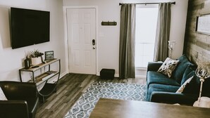 Una sala de estar con televisor, sofá, mesa de centro y alfombra estampada.