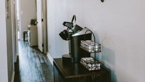 Habitación de hotel con letrero de cafetería, un escritorio con lámpara y una colcha estampada.