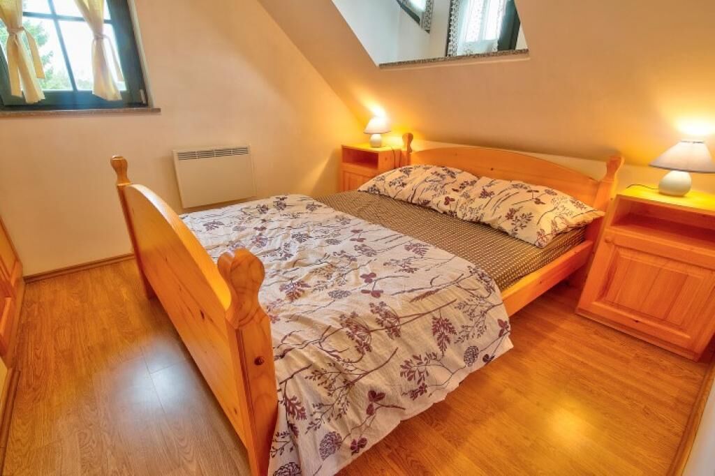 A single bed with a wooden frame, a floral bedspread, and two bedside lamps.