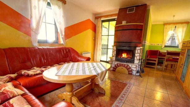 A cozy living room with a red leather sofa, a wooden table, and a fireplace. - Apartment Sara (Vitanje)