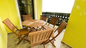 A wooden table and chairs set on a balcony with yellow walls and a tiled floor. - Apartment Sara (Vitanje)