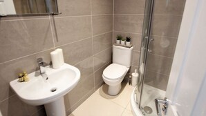 A modern bathroom with a white sink, toilet, and shower. - Spacious 2 Bedroom Duplex (Reading, Berkshire)