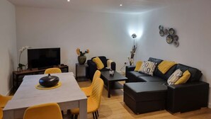 A modern living room with a sofa, a dining table, and a TV. - Spacious 2 Bedroom Duplex (Reading, Berkshire)