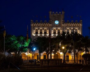 A historic building with a clock tower, arched windows, and a central clock face. - Apartment 5 In front of the sea (Urbanització Santo Tomàs, Es Migjorn Gran)