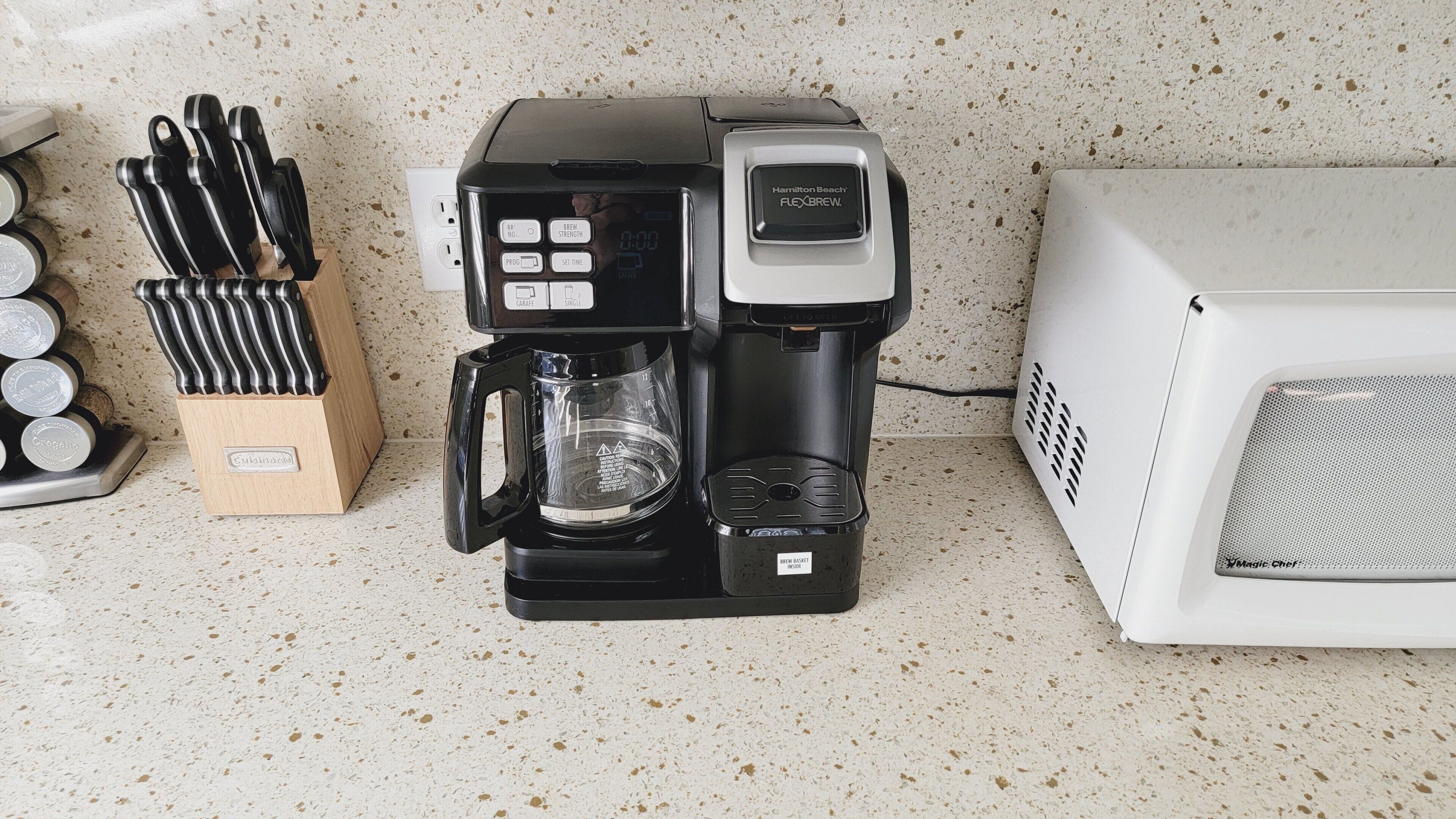 Une cuisine équipée d’une machine à café, d’un four à micro-ondes et d’un bloc à couteaux.