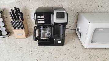 Une cuisine équipée d’une machine à café, d’un four à micro-ondes et d’un bloc à couteaux.