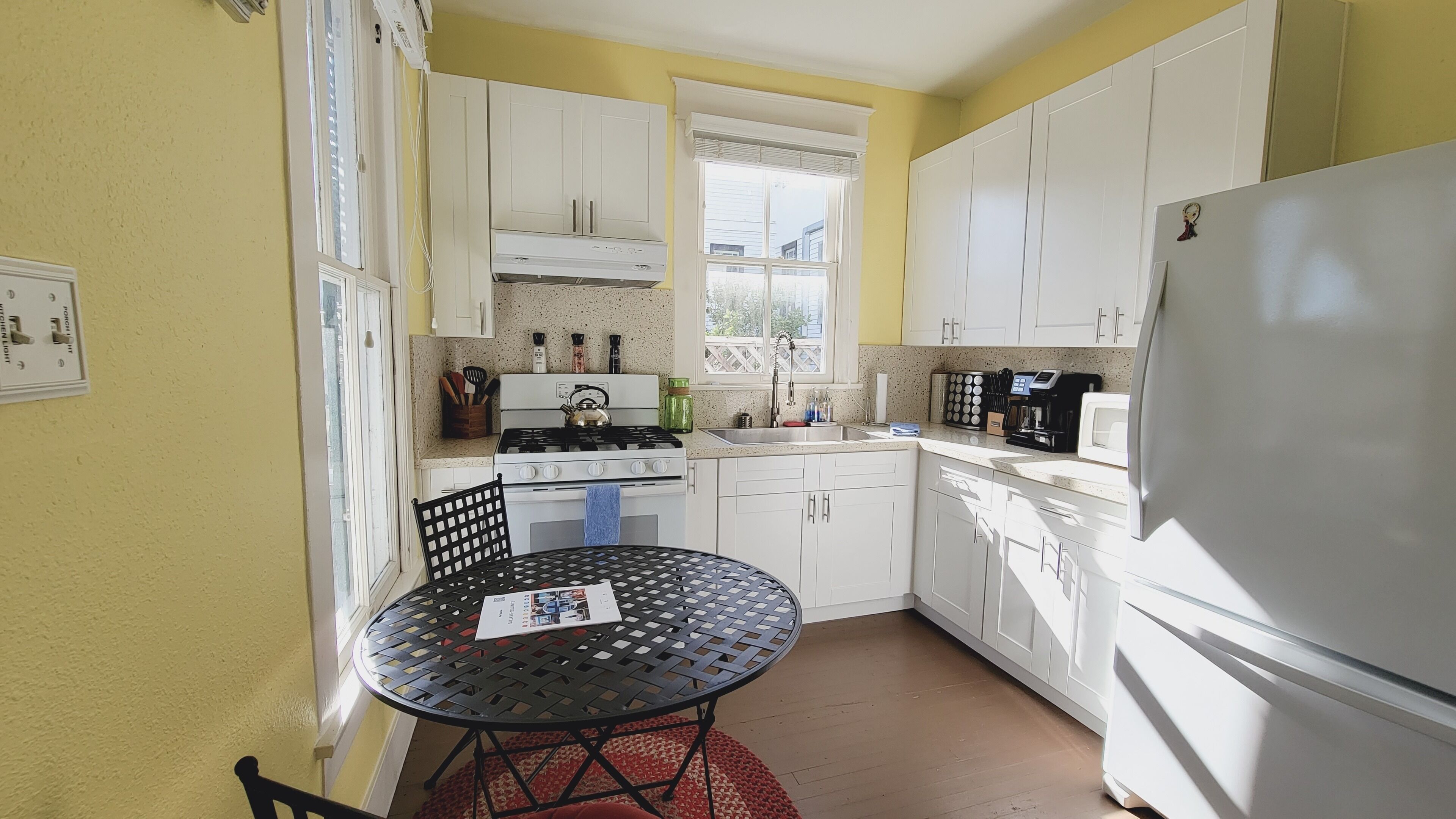 A compact kitchen with white cabinets, a stove, a sink, and a refrigerator.