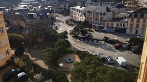 Zona residencial con una mezcla de arquitectura moderna y tradicional, una calle central y coches aparcados.