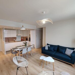 Ein modernes Wohnzimmer mit einem dunkelblauen Sofa, weißen Stühlen und einem Esstisch.