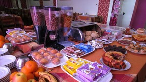 A buffet table with various food items including fruits, pastries, and packaged snacks. - Residencial Pimenta (Portimão)