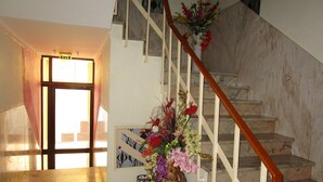 A staircase with a wooden handrail and a floral arrangement on the right. - Residencial Pimenta (Portimão)