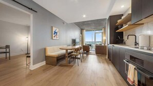 A modern kitchen with a dining area, a sofa, and a view of the outdoors. - Frisco - Rooftop pool & gym on Rainey St (Austin)