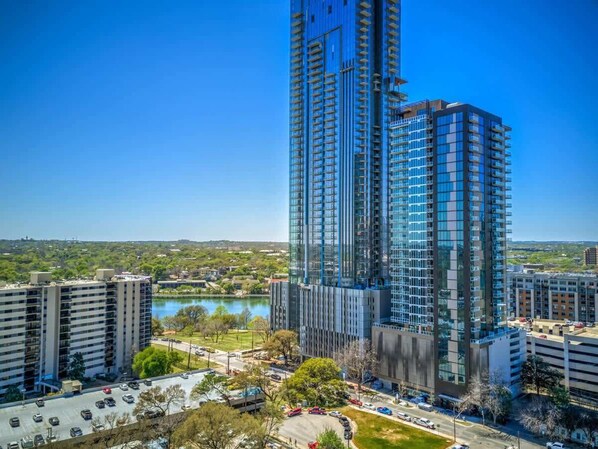 A high-rise building with multiple floors, surrounded by other buildings and a body of water.