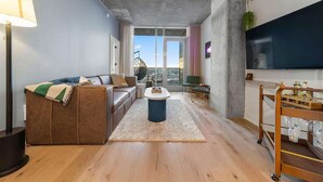 Ein modernes Wohnzimmer mit einer Couch, einem Couchtisch und einem an der Wand befestigten Fernseher.
