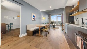 Ein modernes Apartment mit Essbereich, Küche und großem Fenster mit Blick auf die Stadt.
