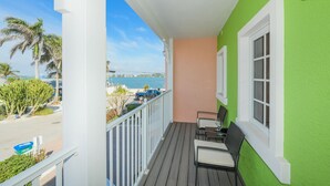 A balcony with a view of the ocean and a bridge, featuring a table and chairs.