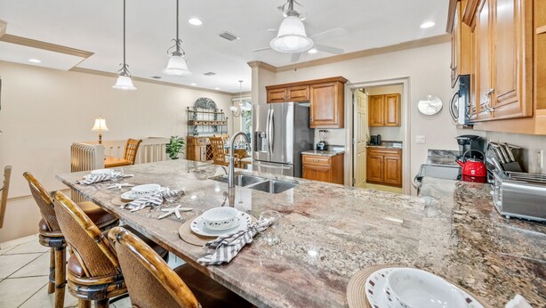 A spacious kitchen with granite countertops, stainless steel appliances, wooden cabinets, and pendant lighting.