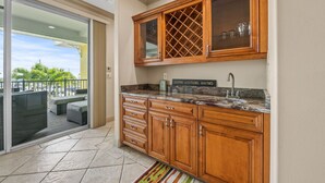 A kitchen with wooden cabinets, a marble countertop, and a built-in wine rack.